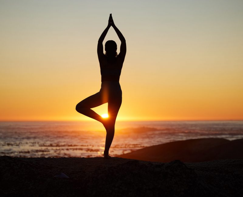 Woman, silhouette or sunset yoga on beach by ocean, sea or water horizon for mental health, relax e.